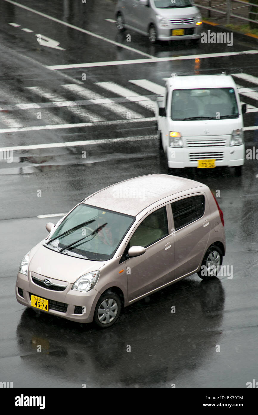 Tokyo, Japan. 8th April, 2015. Cars cross the street under unexpected snow on April 8, 2015 in Hachioji, Tokyo, Japan. This morning the weather forecast reported snow in different areas throughout the country. This is a really unusual phenomenon in Spring, especially during the cherry blossoms season, broadly known for the nice and warm weather. Credit:  Rodrigo Reyes Marin/AFLO/Alamy Live News Stock Photo