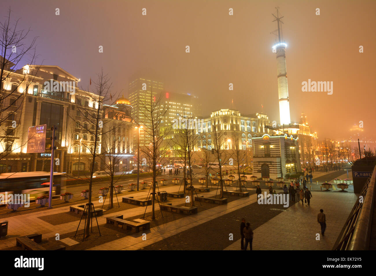 SHANGHAI, CN - MAR 16 2015:Visitors on Shanghai - The Bund or Waitan on foggy night.Shanghai Bund has dozens of historical buildings and It is one of the most famous tourist destinations in Shanghai. Stock Photo