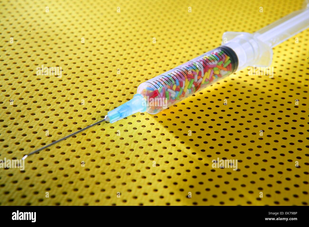 Little colorful candy syringe over yellow background Stock Photo - Alamy