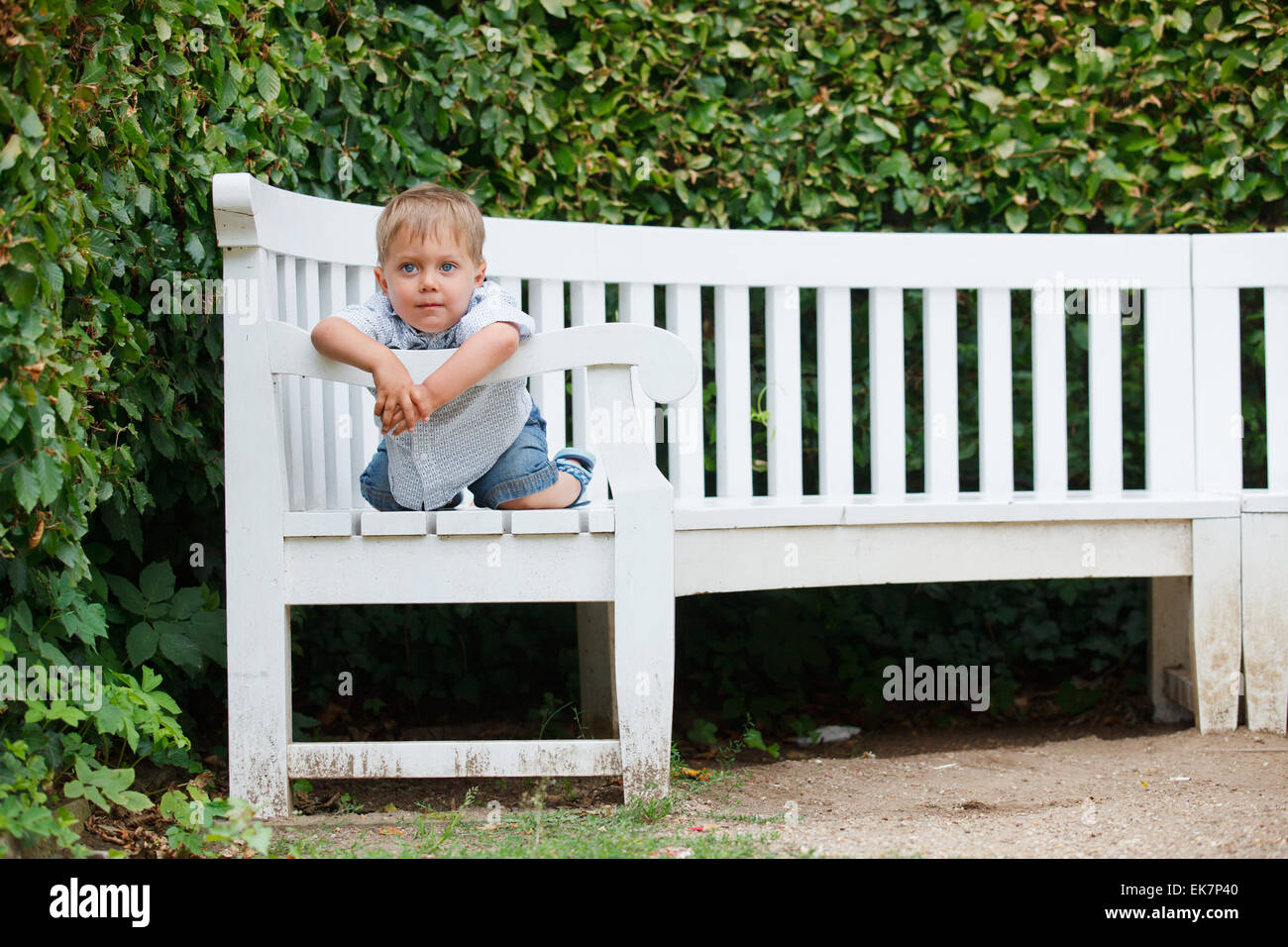 little boy sits on a bench in a park Stock Photo - Alamy