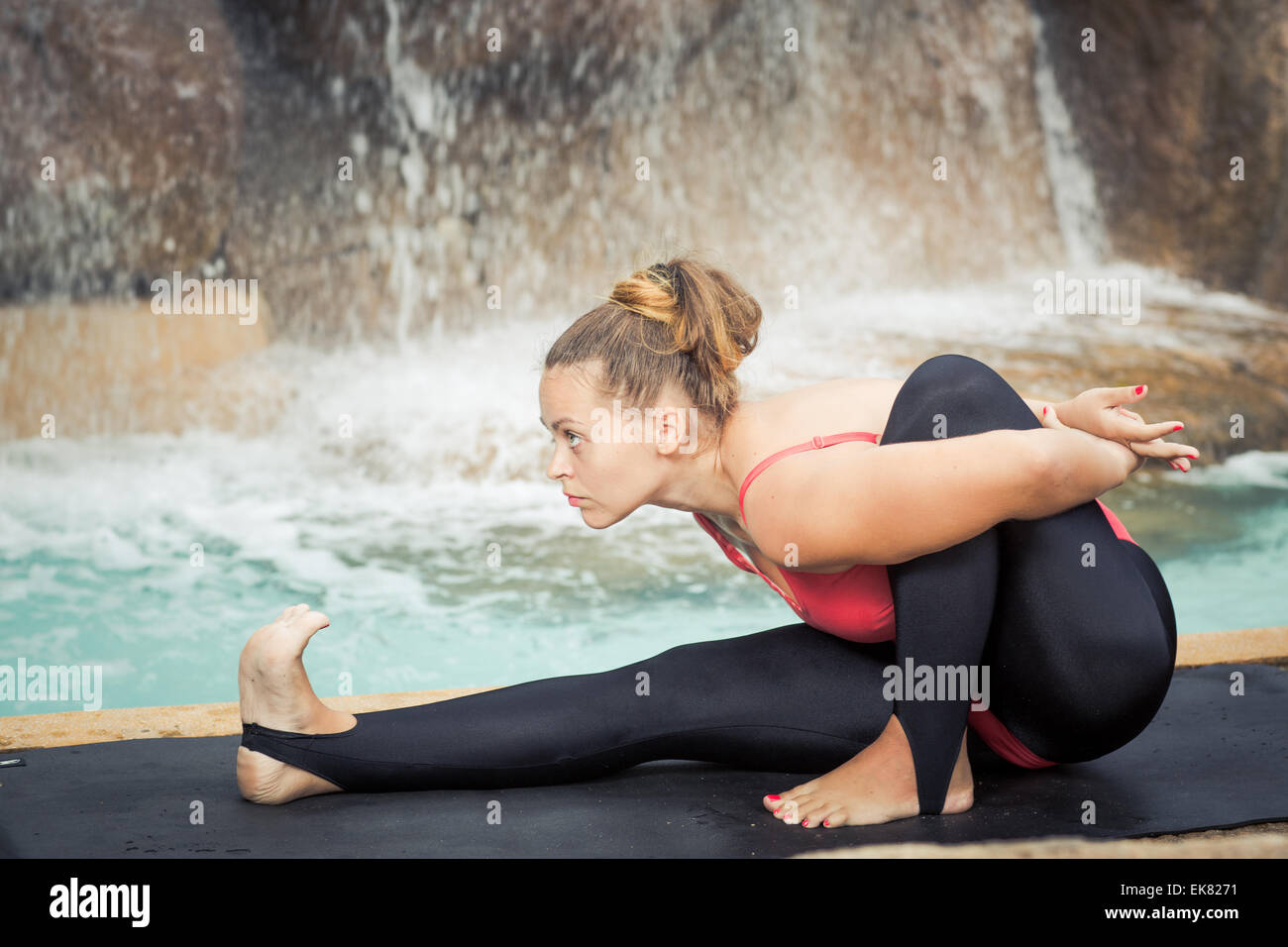 Woman practicing yoga near waterfall. Sage pose. Marichyasana Stock Photo