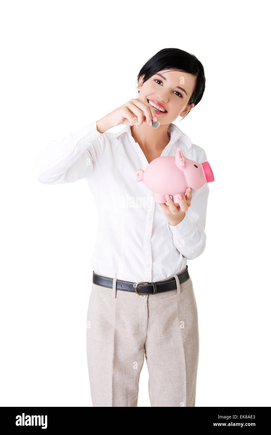 Businesswoman putting a coin into a piggy bank Stock Photo - Alamy