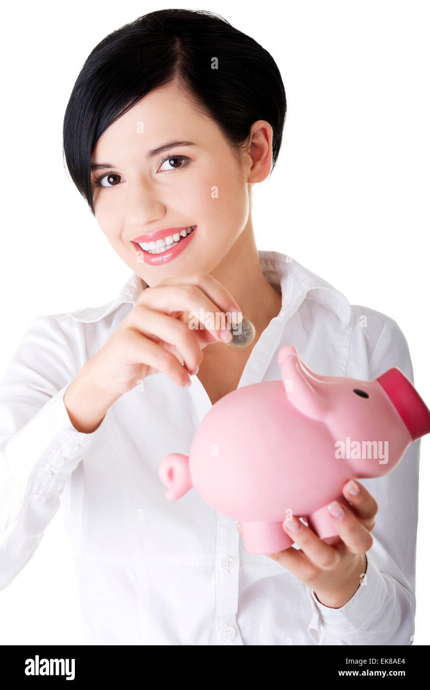 Businesswoman putting a coin into a piggy bank Stock Photo - Alamy