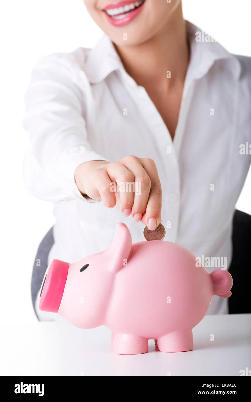 Businesswoman putting a coin into a piggy bank Stock Photo - Alamy