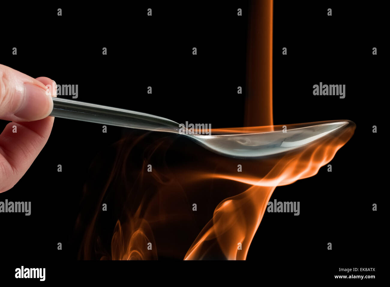 Smoke made to look like fire pouring on a spoon over a black background. Stock Photo