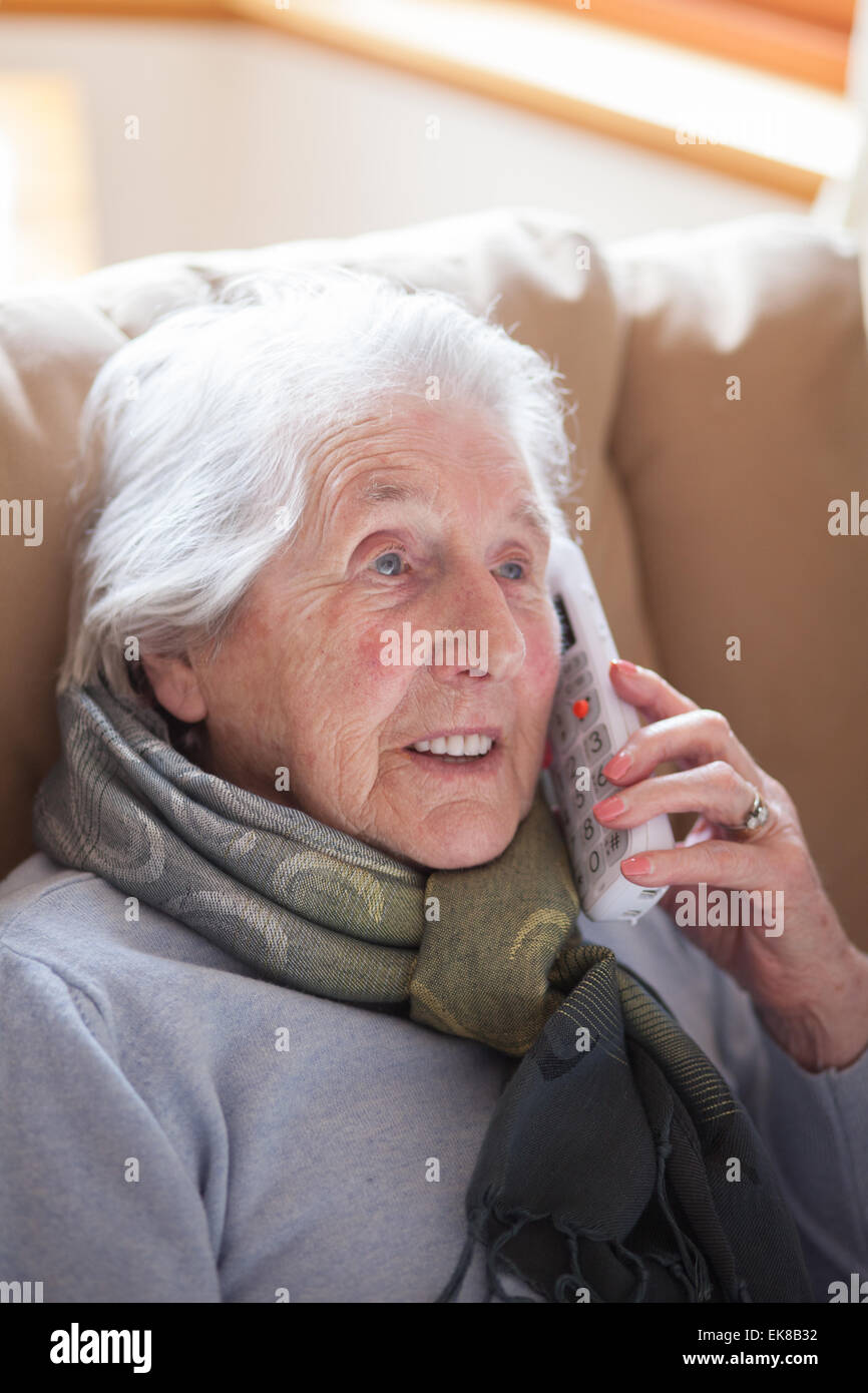 Old lady sitting in easy chair talking on the phone Stock Photo