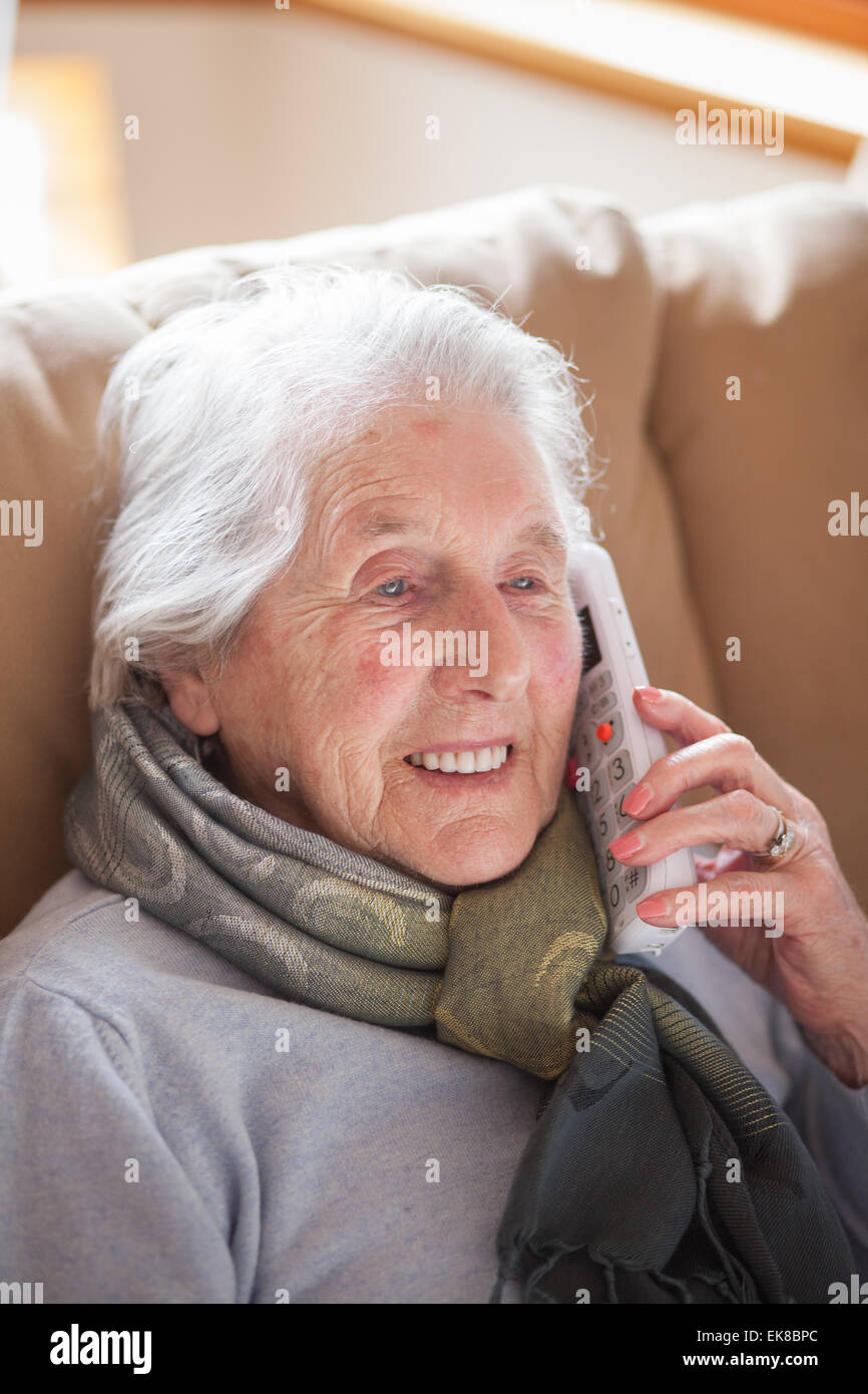 Old lady sitting in easy chair talking on the phone Stock Photo