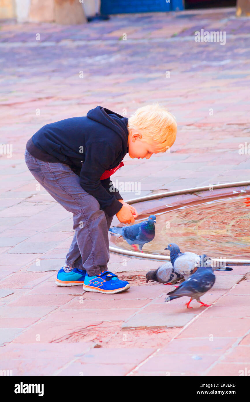 Painterly effect of young boy with pigeons at Ulica Grodzka, Krakow in September Stock Photo