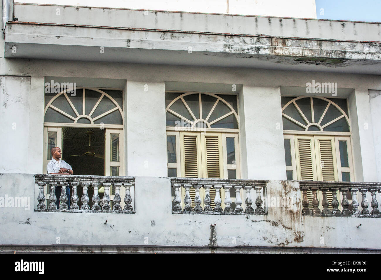 Man on one of three balconies of a build with wonderful architecture but in need of repair in Old Havana in Cuba Stock Photo