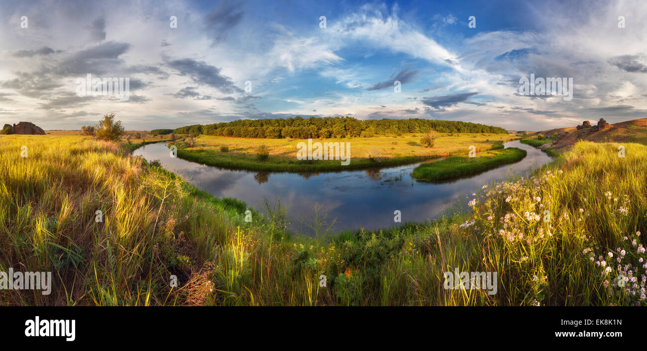 Beautiful summer sunset at the river with blue sky, clouds, yellow grass, green plants and water with reflection  (Ukraine) Stock Photo