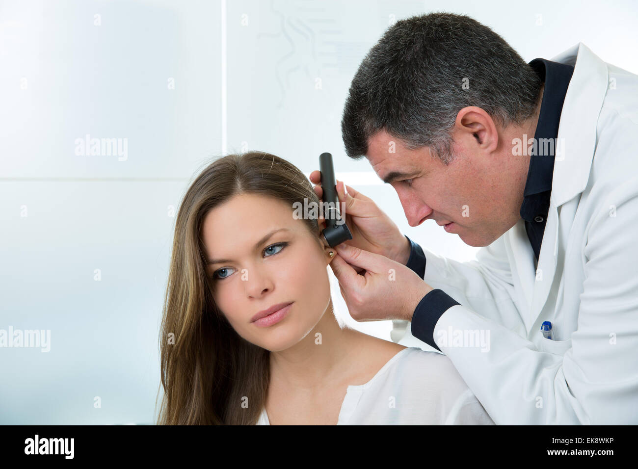 Doctor ENT checking ear with otoscope to woman patient Stock Photo - Alamy