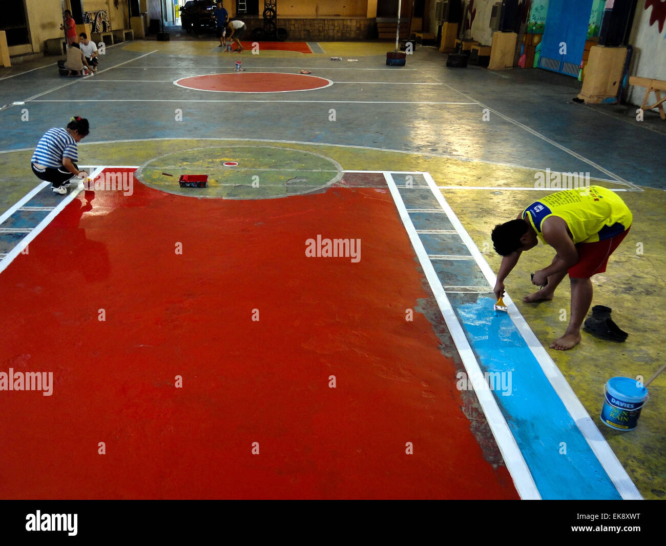 Quezon City, Philippines. 08th Apr, 2015. Filipinos repaint the faded colors of the basketball floor inside the covered court in Barangay Krus Na Ligas. Preparations are being made for the activities leading to the village's festival on the first Sunday of May. © Richard James Mendoza/Pacific Press/Alamy Live News Stock Photo