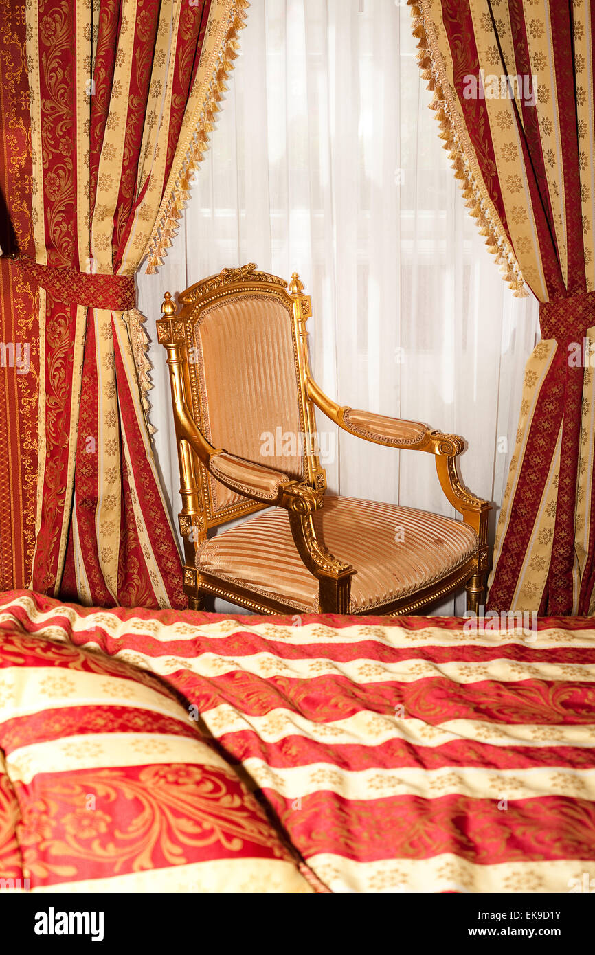 bed and chair in the gold room of the hotel Stock Photo