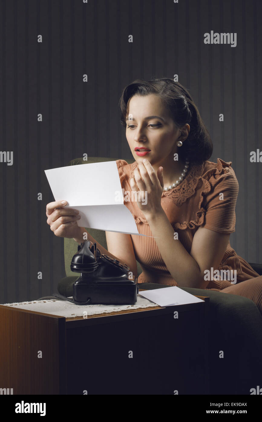 Young woman reading a letter sitting on armchair Stock Photo - Alamy