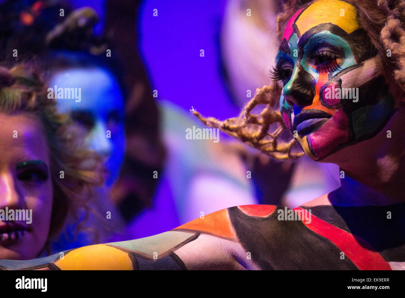 Woman in bright, colourful body and face paint posed on a catwalk stage