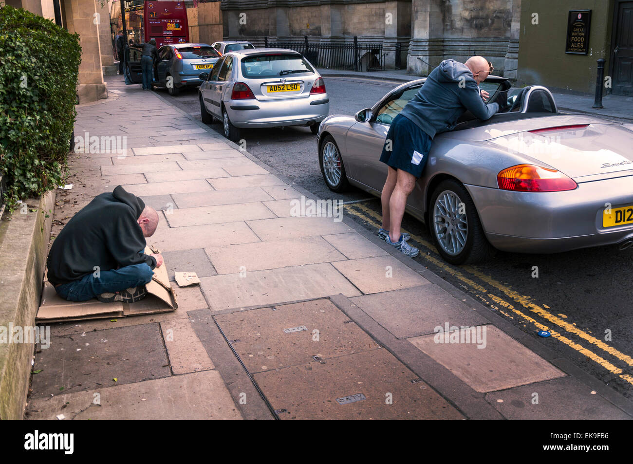 Bath, Somerset, UK. 8th April, 2015. Divided society economically as one man begs and another fills his Porsche Boxster with shopping. Credit:  Richard Wayman/Alamy Live News Stock Photo
