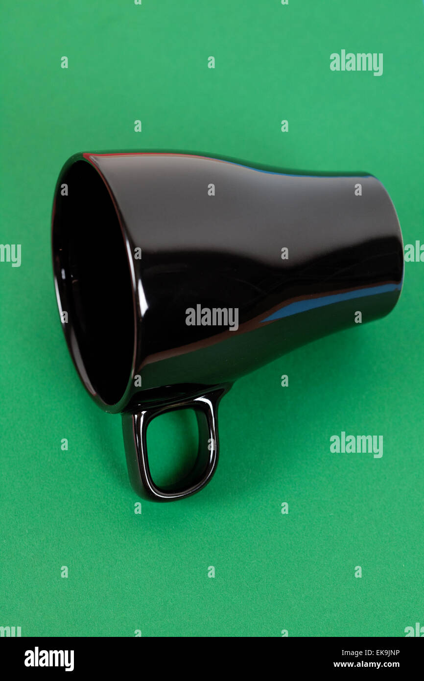 a black cup lying on green  background Stock Photo