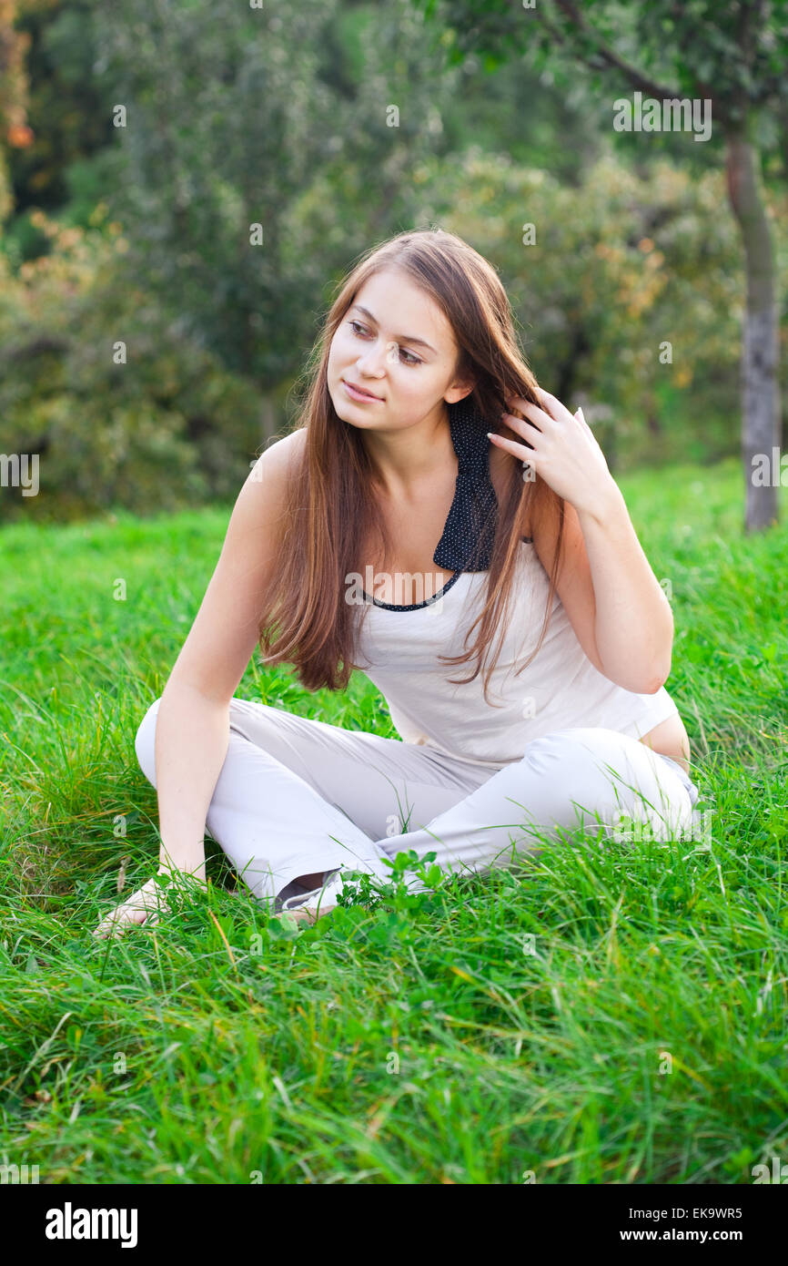 beautiful young woman sitting on green grass Stock Photo - Alamy