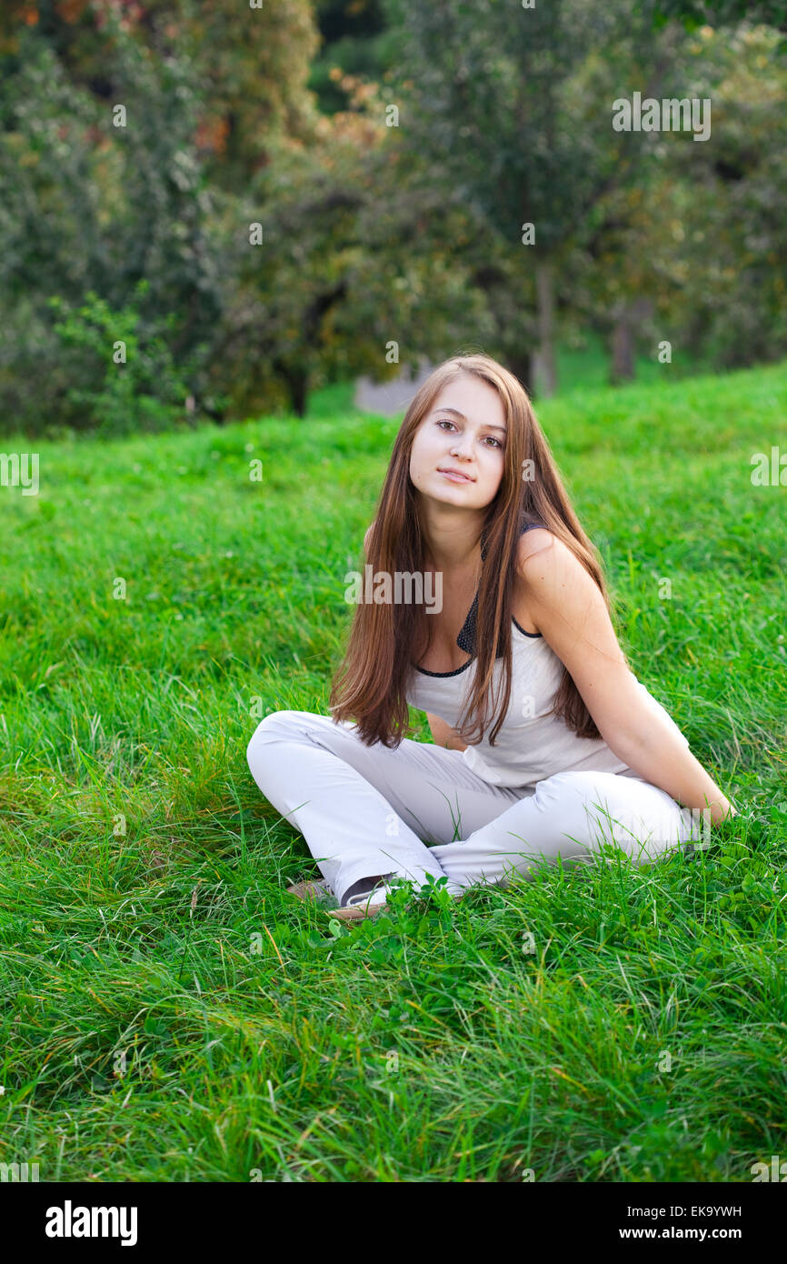 beautiful young woman sitting on green grass Stock Photo - Alamy