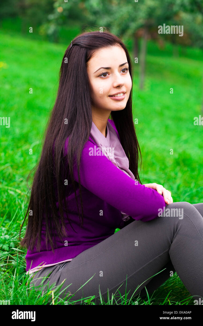 beautiful young woman sitting on green grass Stock Photo - Alamy