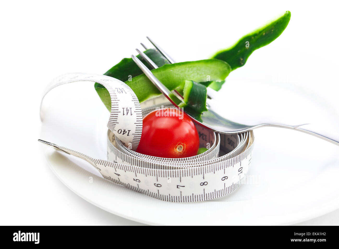 tomato,fork ,cucumber skin and measure tape on a plate isolated Stock Photo