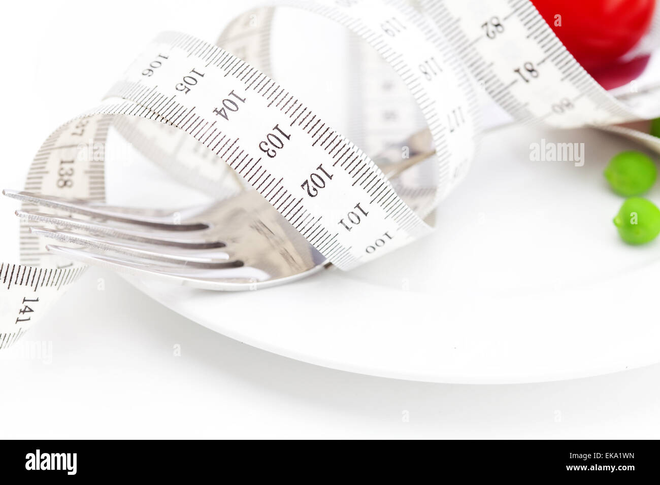 tomato,fork ,peas and measure tape on a plate isolated on white Stock Photo