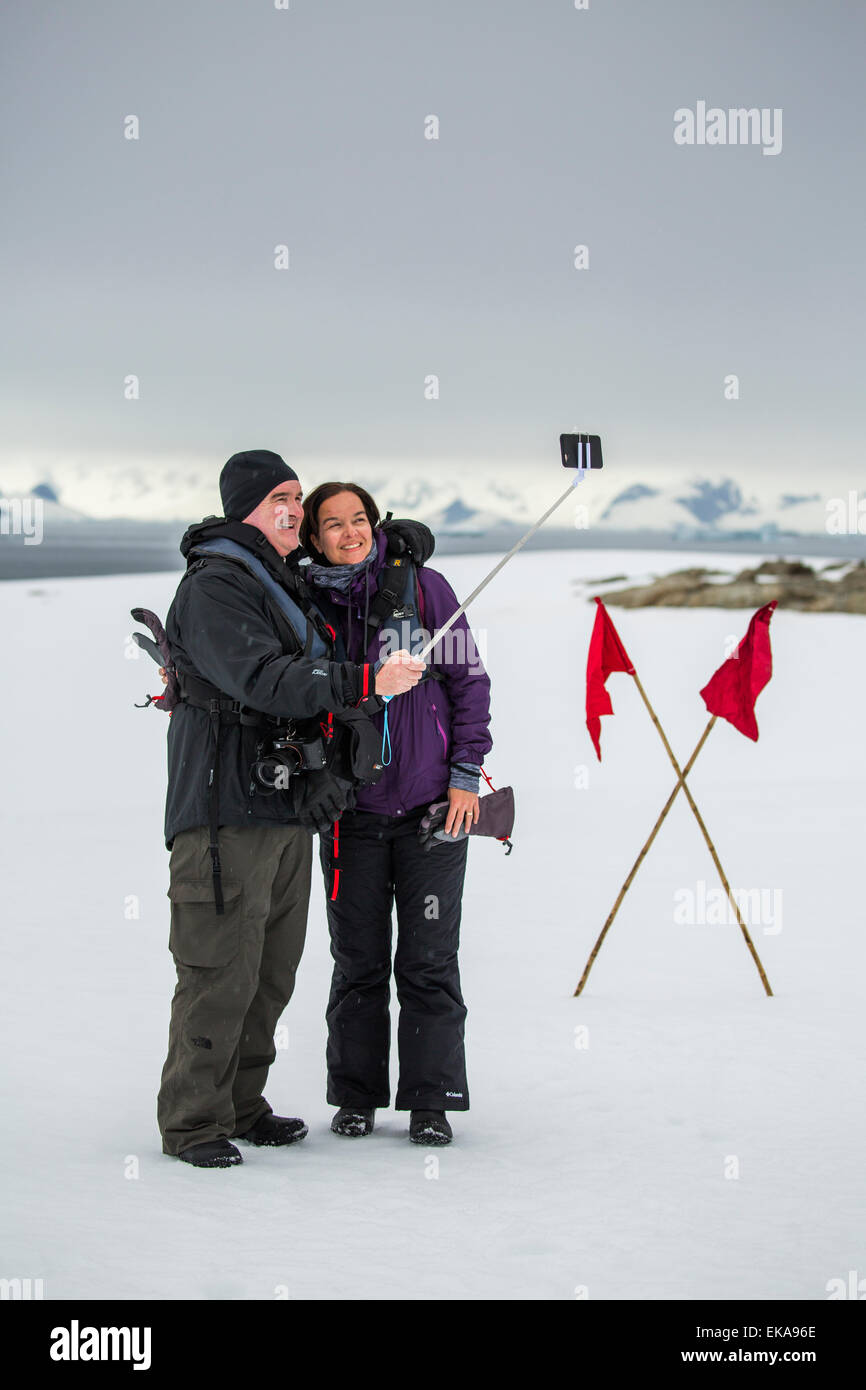 couple taking photograph with selfie stick, Winter Island, Antarctica. Stock Photo