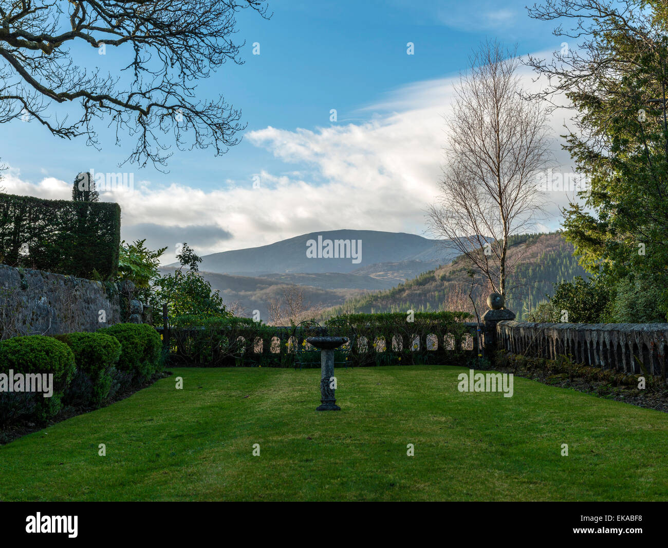 Welsh Landscape, scenic garden setting, with shrub borders, stone feature walling, grass lawn with a forest & countryside vista Stock Photo