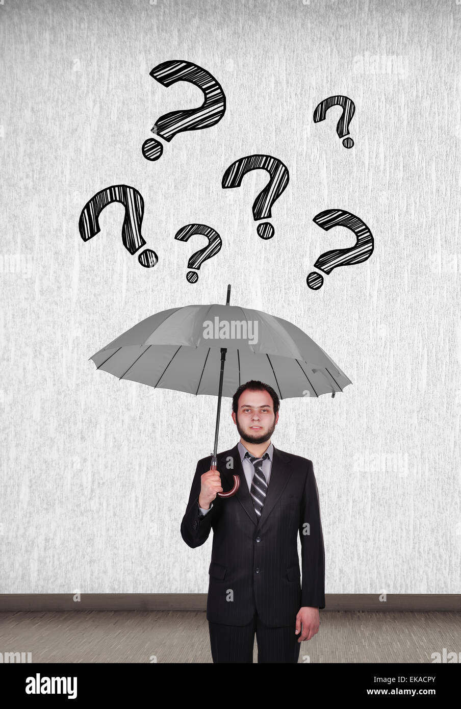 young businessman holding umbrella and falling question mark Stock