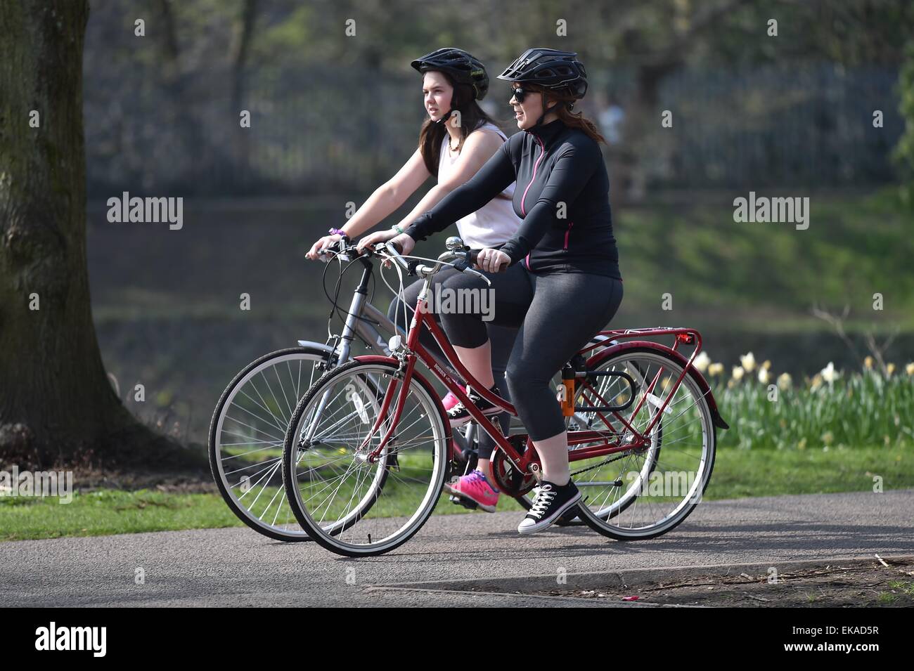 Two female cyclists ride bikes on the Taff Trail in Cardiff, South Wales, during warm sunny weather. Stock Photo