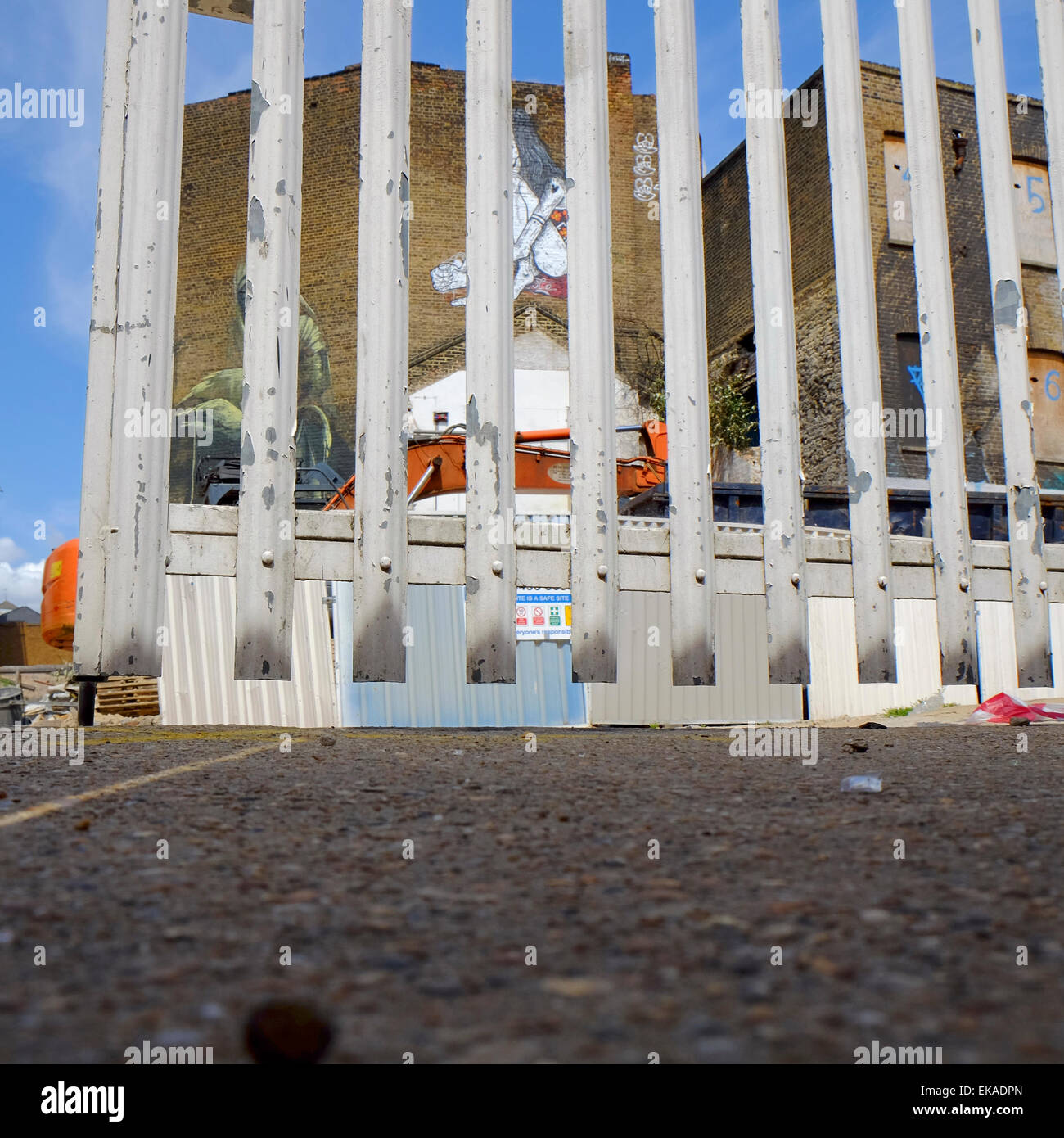 Galvanized steel gate to a development plot with graffiti covered derelict houses in East London Stock Photo