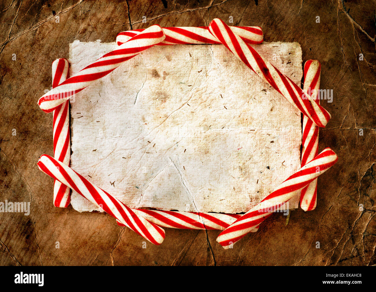 Christmas border with a red and white candie canes  around blank paper as a copy space on wooden planks, wooden table background, New year theme Stock Photo