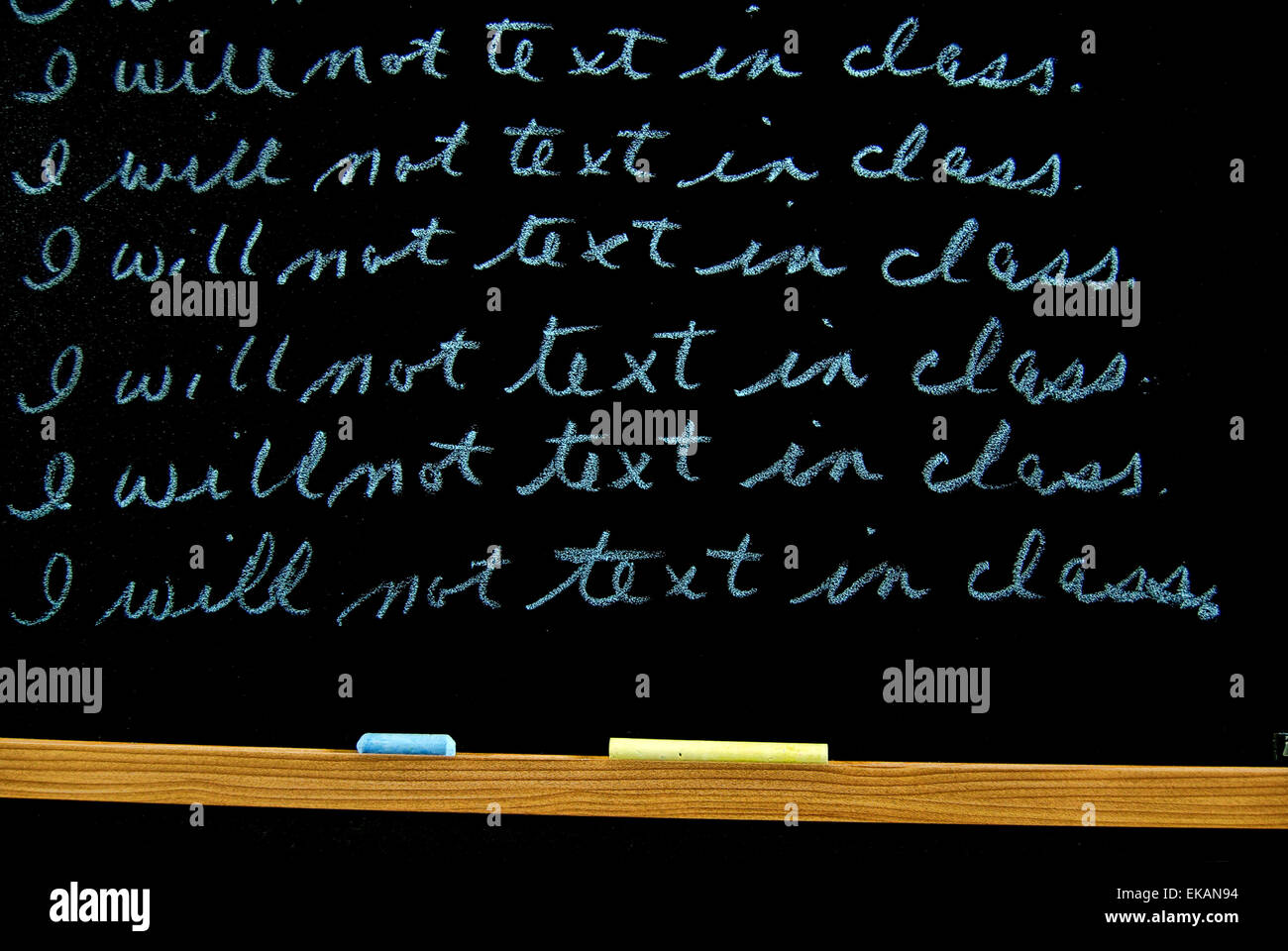 Written lines for punishment on a black chalkboard with chalk. Stock Photo