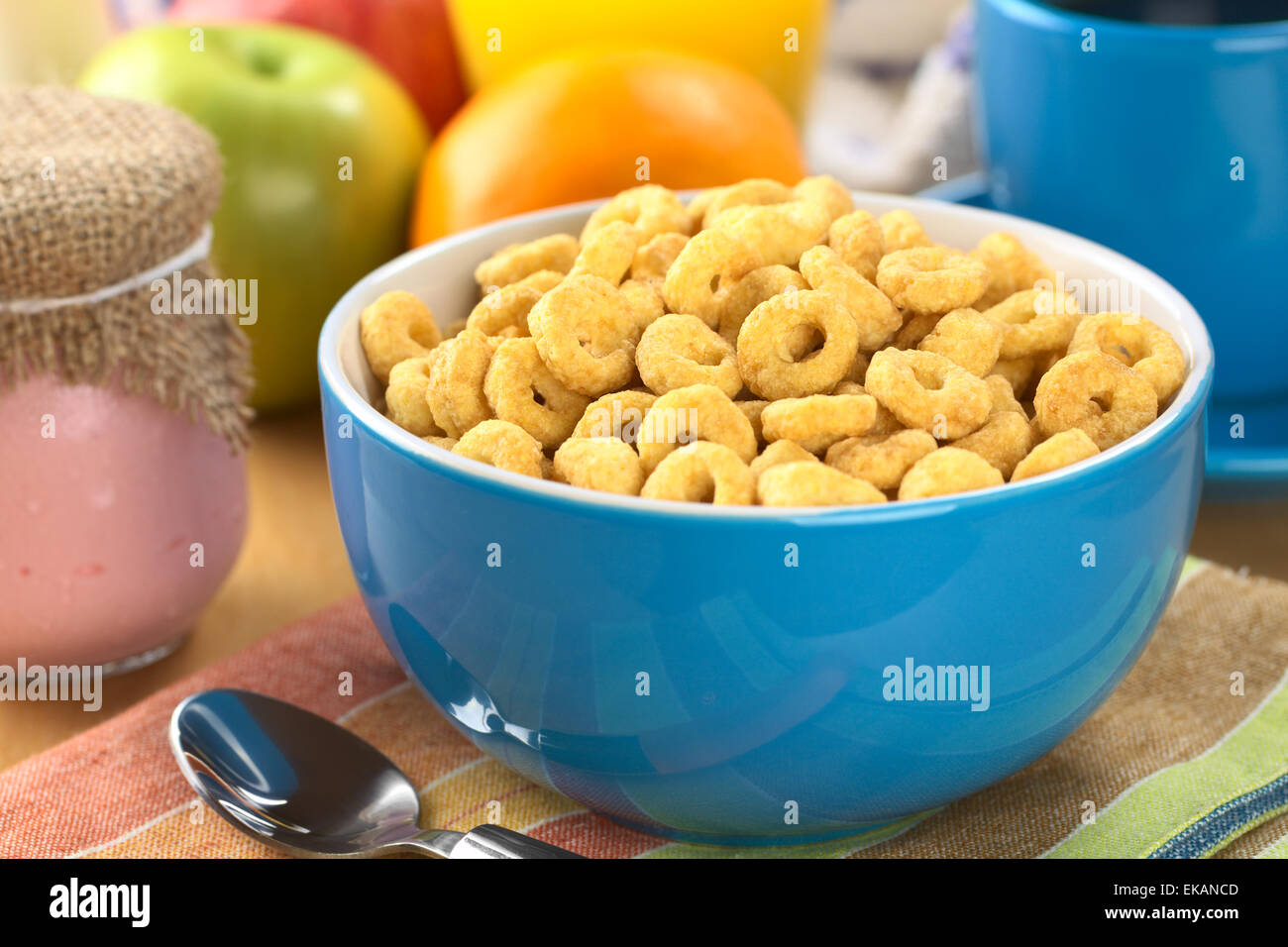 A bowl full of honey flavored cereal loops, yogurt in glass, fresh