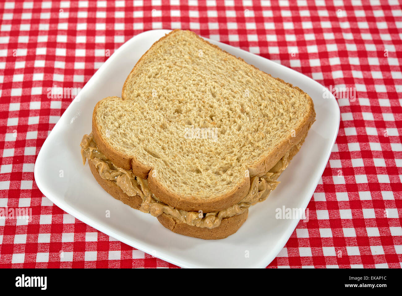 Peanut butter sandwich on whole wheat bread on a square white plate. Stock Photo