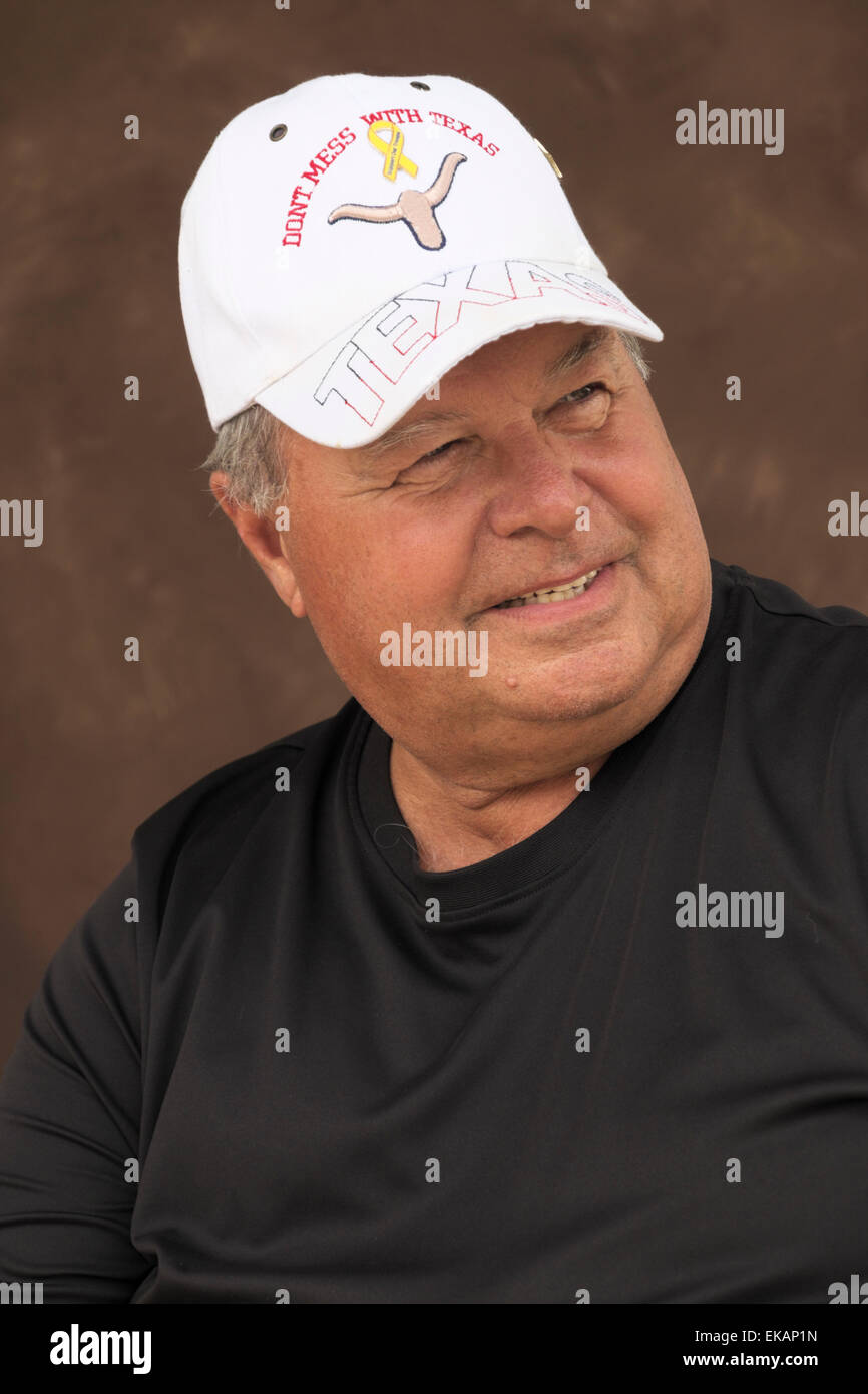 Elderly man poses for a formal portrait wearing a Texas cap. Stock Photo