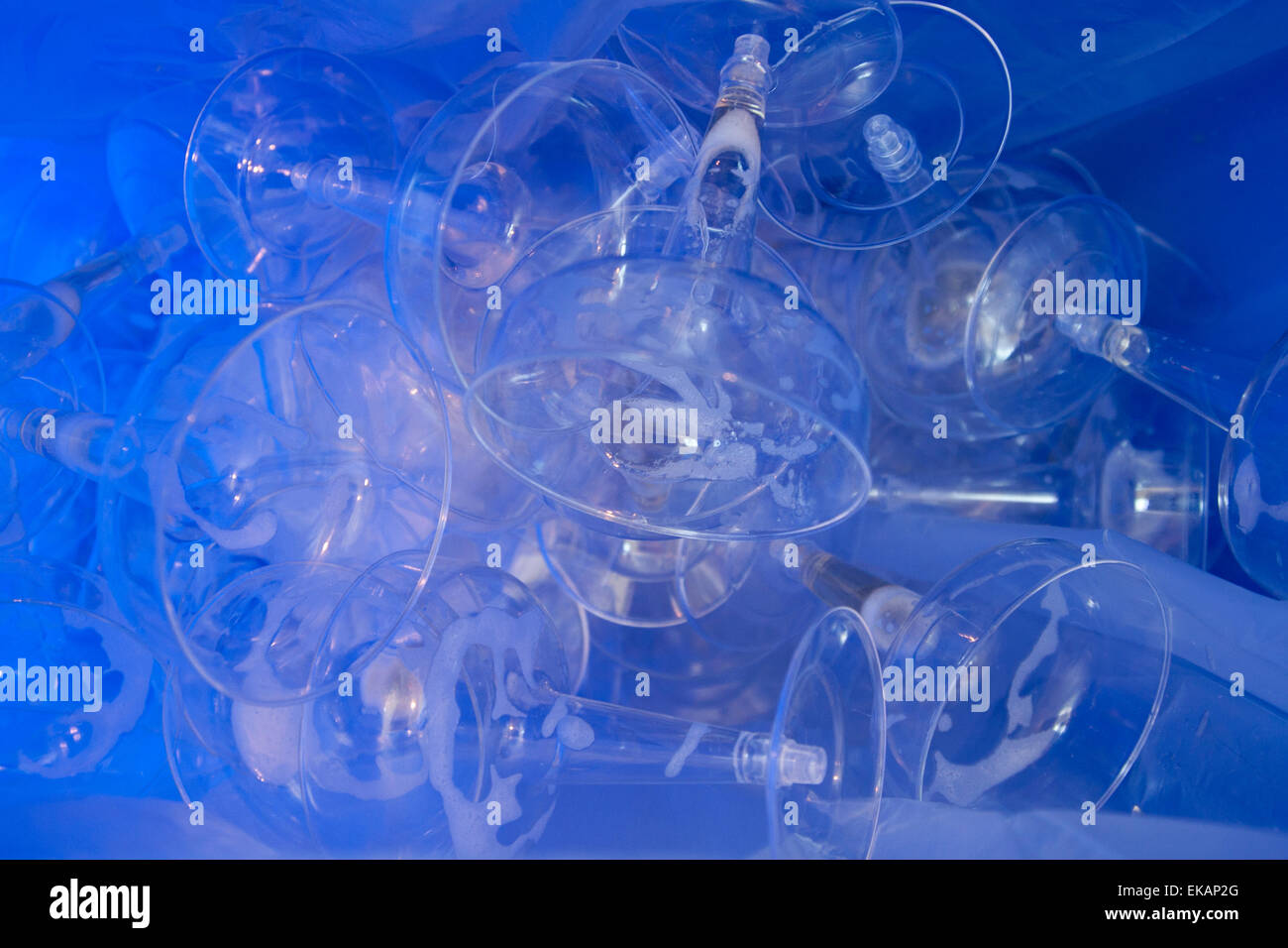 Used plastic champagne glasses in a recycling container at an art