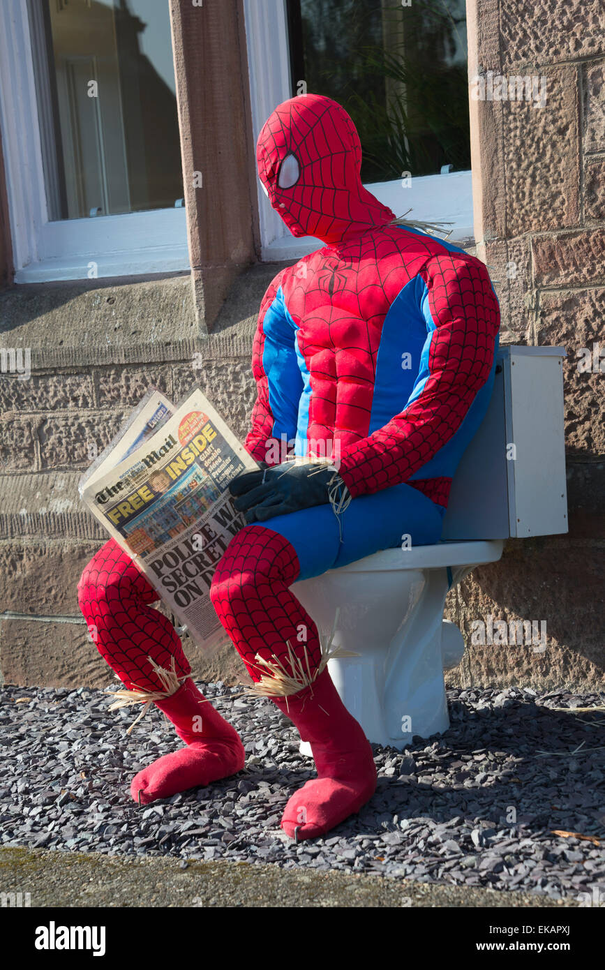 Spiderman scarecrow at scarecrow festival. Sitting on toilet reading newspaper. Stock Photo