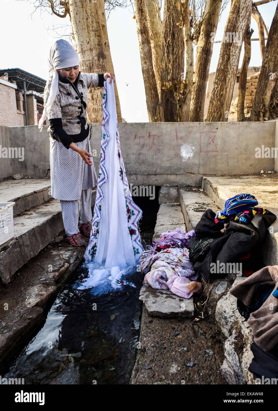 (150409) -- TURPAN, April 9, 2015 (Xinhua) -- A resident washes clothes in a canal of a karez irrigation system in Turpan, northwest China's Xinjiang Uygur Autonomous Region, April 3, 2015. The karez wells are vertical shafts and subterranean canals that surface in the form of ditches and small ponds. The karez irrigation system, which are composed of vertical shafts, subterranean and ground canals, and small reservoirs, was built 2,000 years ago and is considered one of China's greatest surviving ancient man-made structures, along with the Great Wall and the Grand Canal. Turpan, the Stock Photo