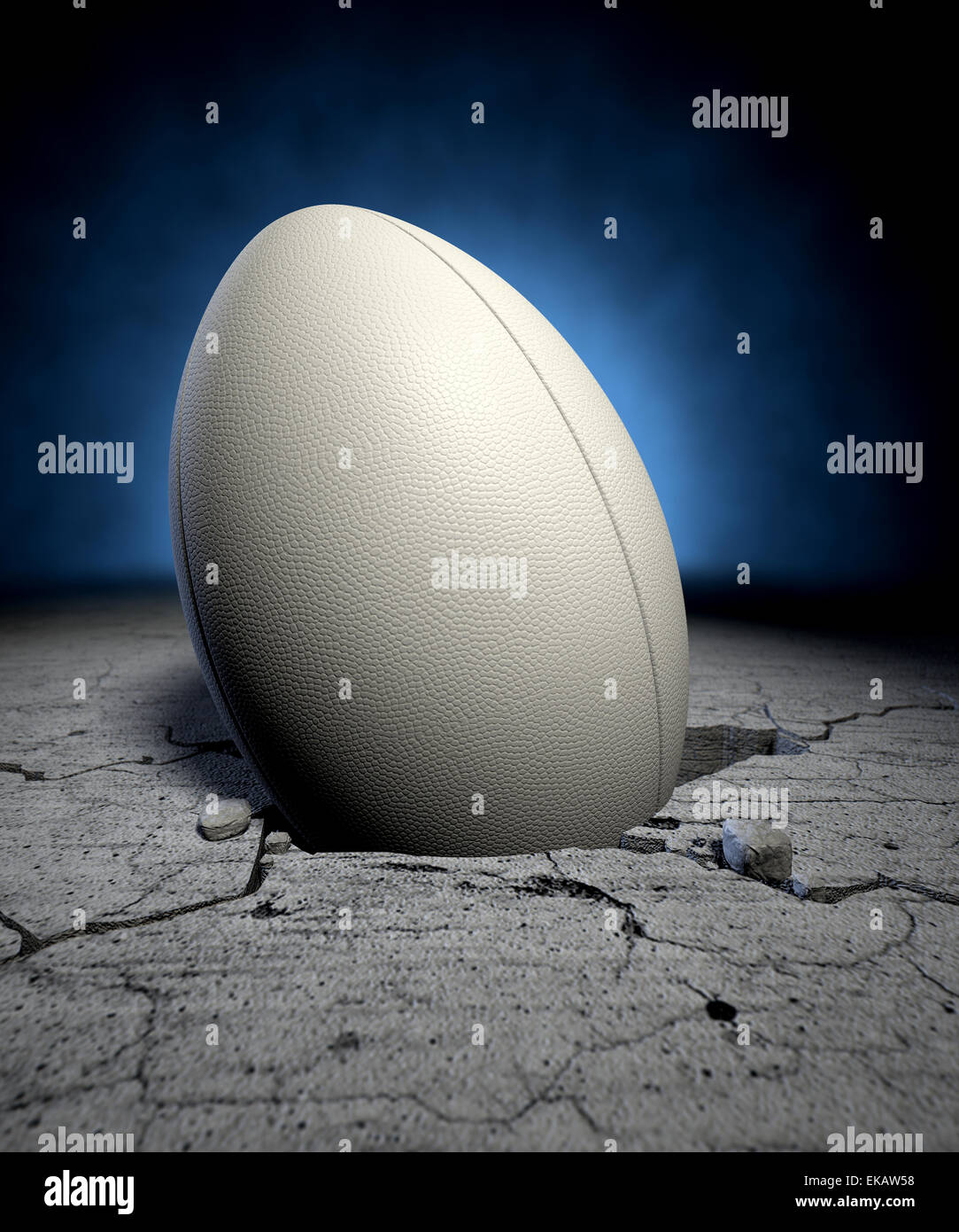 A white dimpled rugby ball stuck in a whole cracked in the ground on a ...