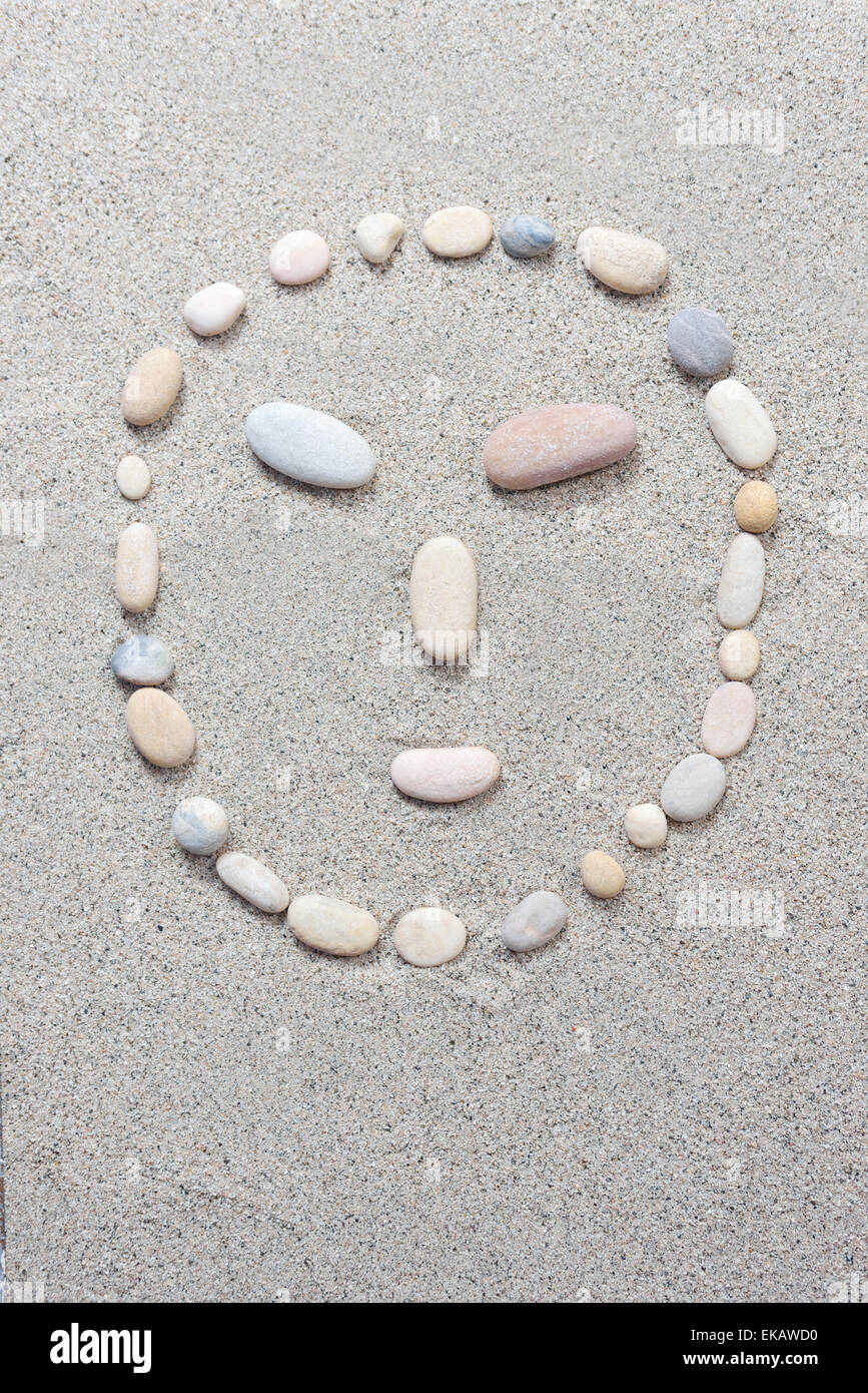 Pebble smiling isolated on a sand background Stock Photo