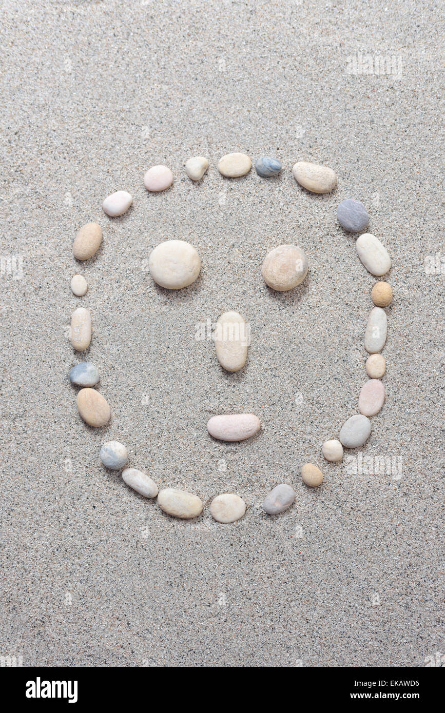 Pebble smiling isolated on a sand background Stock Photo