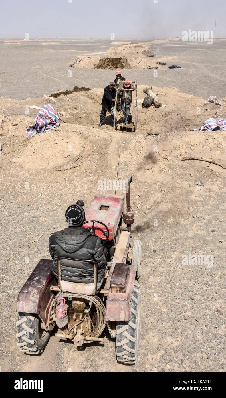 (150409) -- TURPAN, April 9, 2015 (Xinhua) -- Dredging worker Ablimit Yagufu and his family members try to dredge a karez well in Turpan, northwest China's Xinjiang Uygur Autonomous Region, April 3, 2015. The karez wells are vertical shafts and subterranean canals that surface in the form of ditches and small ponds. The karez irrigation system, which are composed of vertical shafts, subterranean and ground canals, and small reservoirs, was built 2,000 years ago and is considered one of China's greatest surviving ancient man-made structures, along with the Great Wall and the Grand Canal. Stock Photo