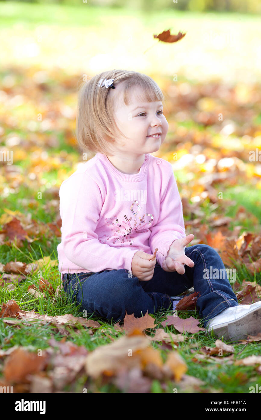 beautiful little girl sitting on the autumn leaves Stock Photo - Alamy
