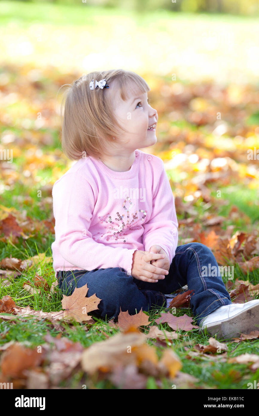 beautiful little girl sitting on the autumn leaves Stock Photo - Alamy