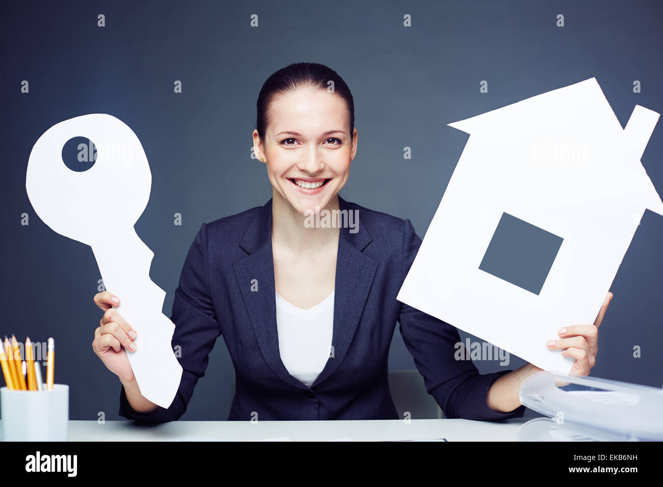 Cheerful businesswoman with paper house and key Stock Photo - Alamy