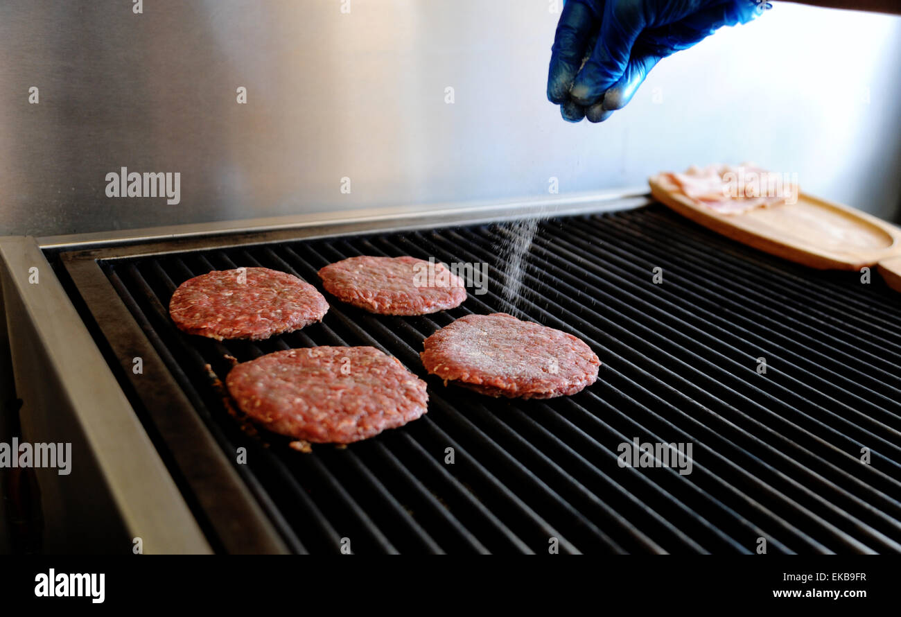 Freshly made beef burgers cooking on a hot griddle at a fast food take