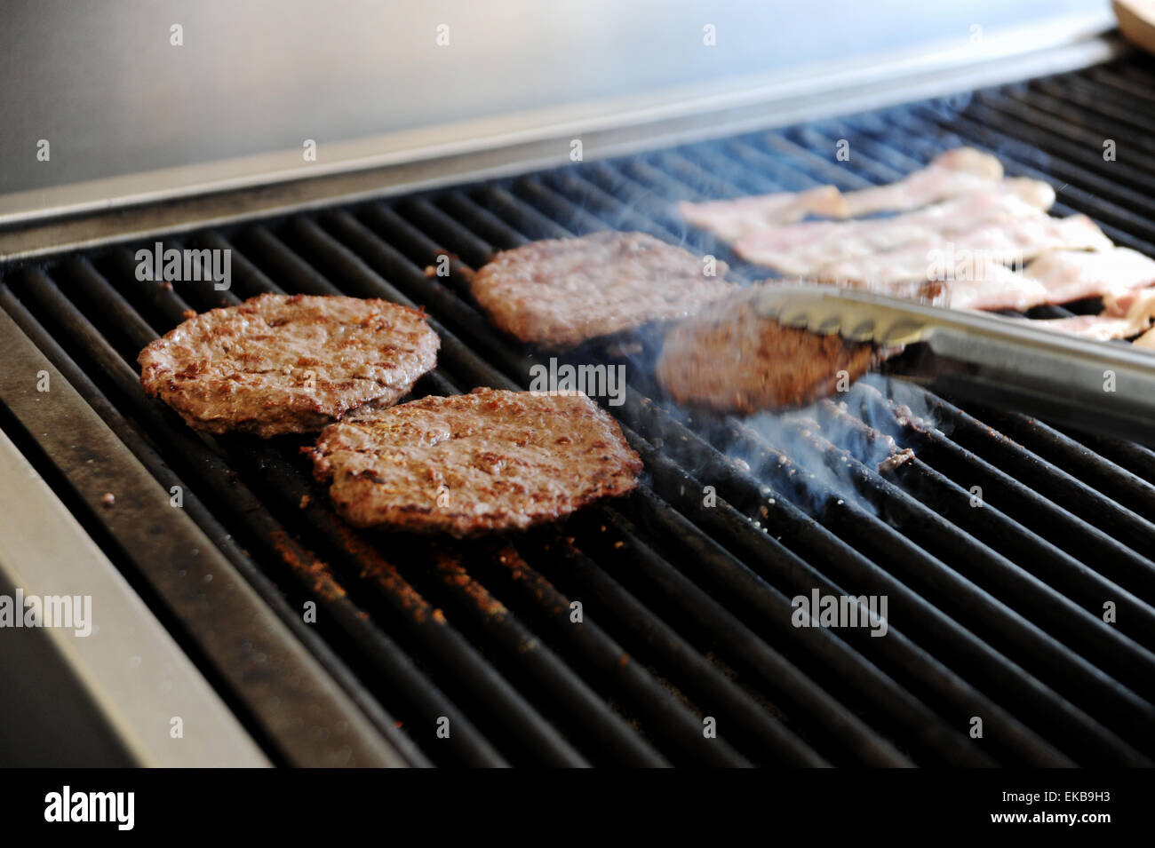 Freshly made beef burgers cooking on a hot griddle at a fast food take away shop Stock Photo