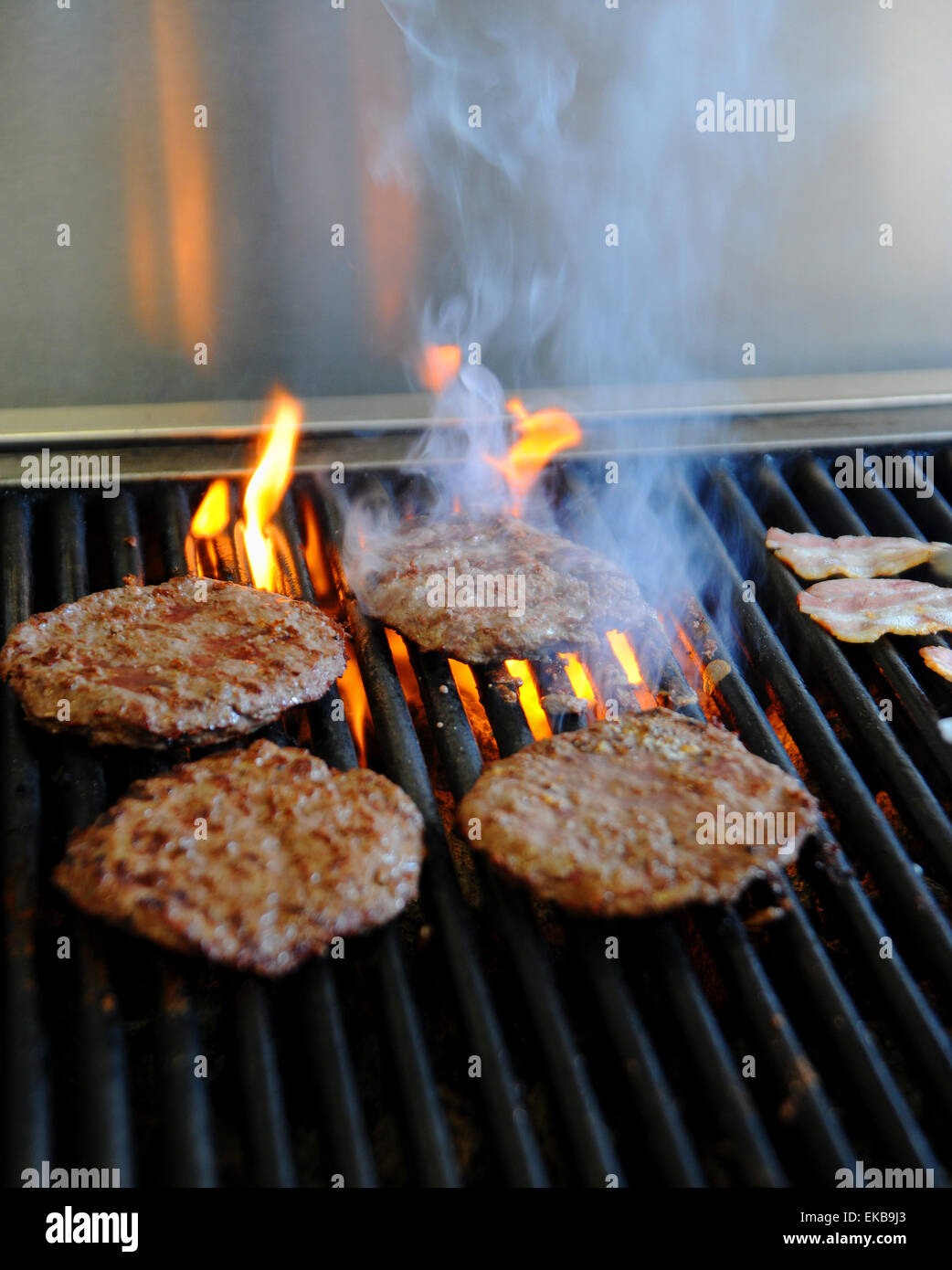 Freshly made beef burgers cooking on a hot griddle at a fast food take away shop Stock Photo