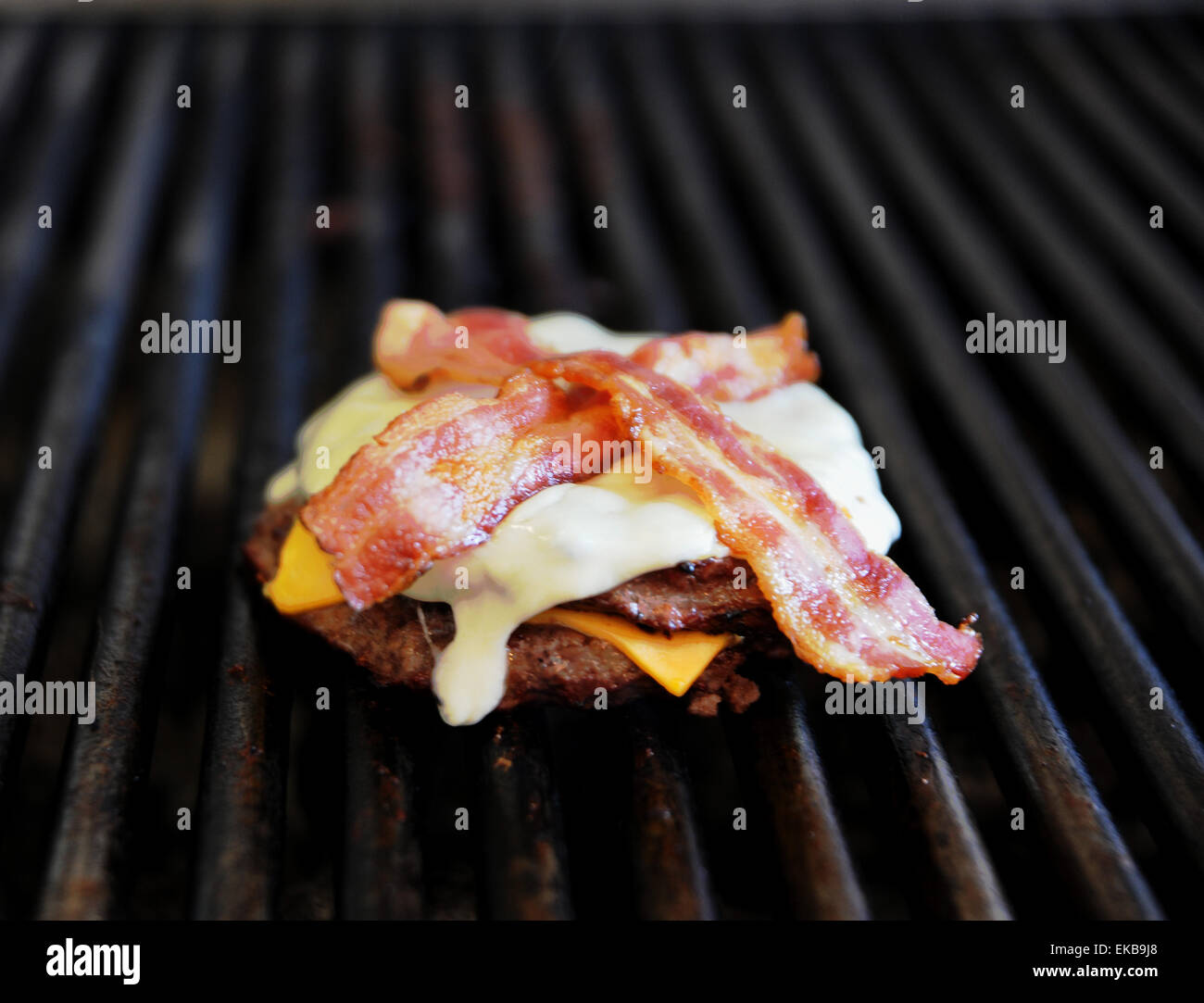 Burger with cheese and bacon melting on a hot griddle Stock Photo Alamy